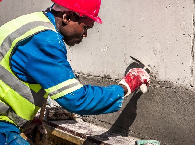 A plasterer skimming a concrete wall on site
